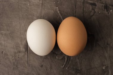 İki yumurta, beyaz ve kahverengi koyu arka plan üzerinde. Kopya alanı 