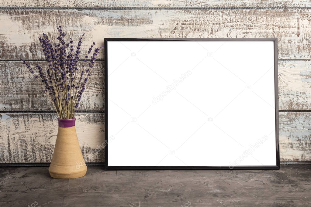 Mock up of an empty frame poster on a wall of wooden boards. A bunch of lavender in a vase  