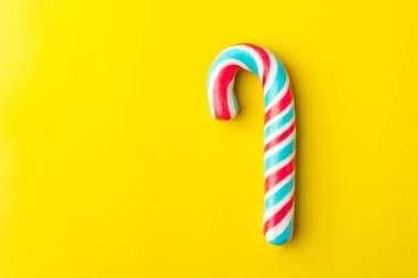 Sarı arka plan üzerinde renkli yay ile Noel şeker kamışı. Kopya alanı  