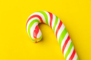 Sarı arka plan üzerinde renkli yay ile Noel şeker kamışı. Kopya alanı  