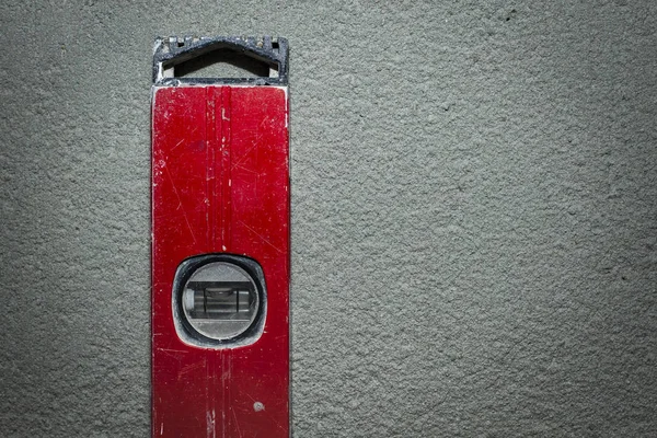 Old construction tool, red color level on concrete background. Copy space