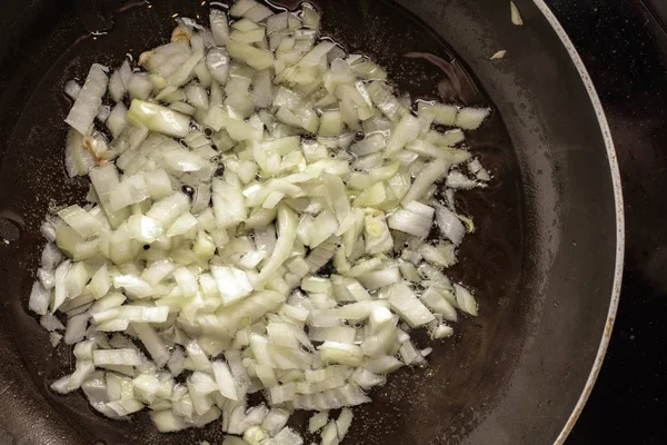 Fried onions in oil in a pan. Top view