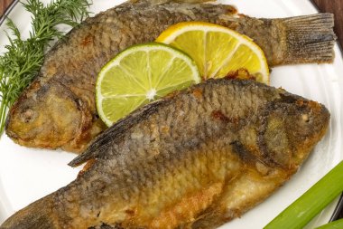 Limon dilimleri ile limon dilimleri ve taze otlar ile dekore ızgara Crucian balık. bitmiş çanak closeup