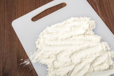 Beyaz kesme tahtasında buğday unu. Ahşap arka plan. Kopyalama alanı