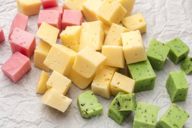 Peynir küpleri yeşil, sarı ve kırmızı renk buruşturulmuş kağıt arka plan üzerinde. Şarap için atıştırmalık. Üstte görüntü