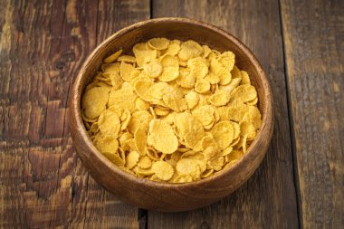 Tahta bir masanın üzerindeki tabakta mısır gevreği. Yakından kapatın. Üstte görüntü