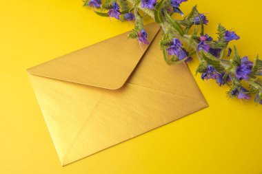 Sarı bir arka plan üzerinde altın bir zarf, mavi çan güzel bir sprig ile. Kopyalama alanı