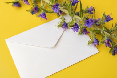 Sarı bir arka plan üzerinde beyaz bir zarf, mavi çan güzel bir sprig ile. Kopyalama alanı