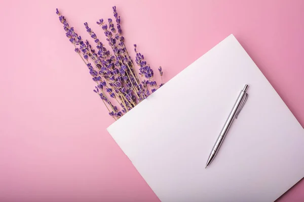 blank notebook with a metal fountain pen and lavender flowers. mock up for your design. Pink background