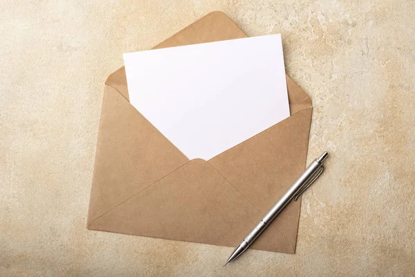 Kraft zarfında açık bir arka plan üzerinde boş kağıt. İmzalarınız için kartpostal temizleyin. Üstte görüntü