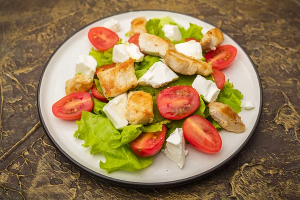 Warm salad with chicken, cherry tomatoes and soft cheese cheese. dressing with olive oil. Dietary meal