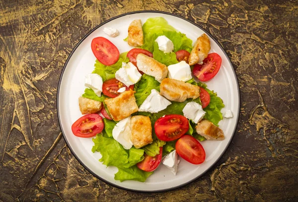 Warm salad with chicken, cherry tomatoes and soft cheese cheese. dressing with olive oil. Dietary dish. Top view