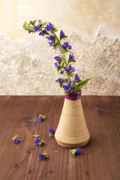 Blue flowers in a vase on a wooden table. Copy space for your text