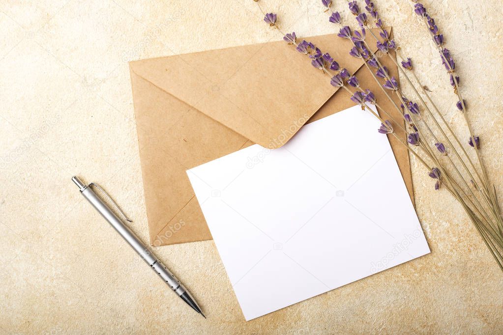 Blank paper with Kraft envelope and lavender flowers on a light background. Clean postcard for your signatures