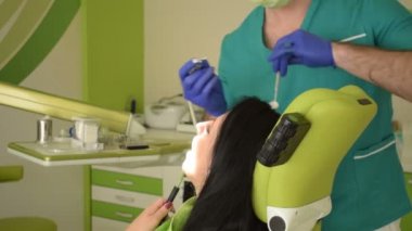 Onun erkek dişçi dişlerini giderir iken diş sandalye üzerinde oturan genç kadın