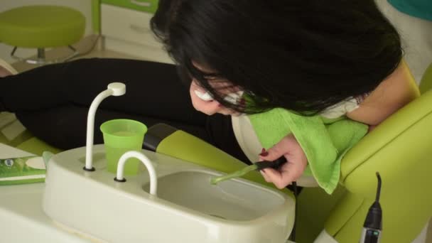年轻妇女在牙科办公室冲洗她的嘴与治疗 — 图库视频影像
