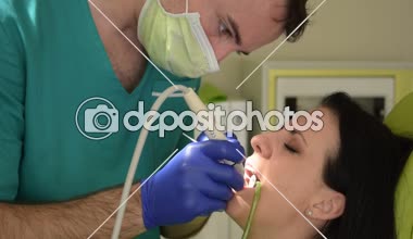 Onun erkek dişçi dişlerini giderir iken diş sandalye üzerinde oturan genç kadın