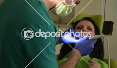 Erkek diş hekimi diş kadın hastanın tamir ediyor.