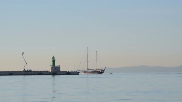 Sailboat Leaves Port Passes Lighthouse — Stock Video