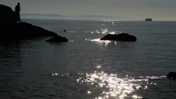 Silhouette Uomini Sulle Rocce Mare Mentre Barca Naviga Sullo Sfondo — Video Stock
