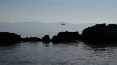 Kruvazör ve deniz kaya siluetleri arka planda gemi