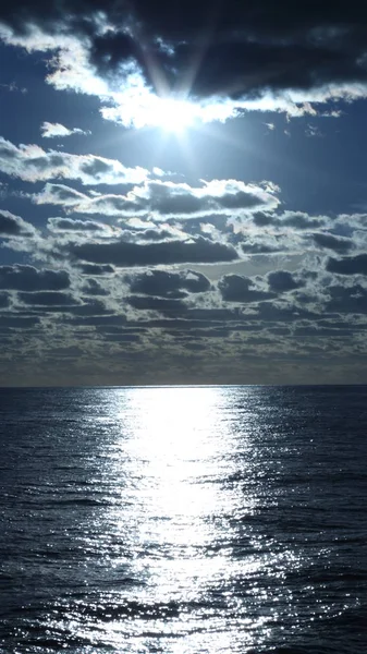Sun and cloudy sky above the ocean