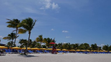 caveharvest Caye, Belize - 16 Mayıs 2017 hasat: geniş mavi plaj sandalyesi kırmızı şemsiye ile hasat Caye sahilde oturup bir cankurtaran uzanmış sandalye uzanmanız vurdu.