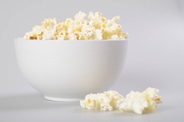 Beyaz arka planda beyaz kase karamel patlamış mısır.