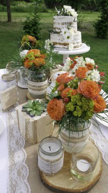  Ahşap elemanları turuncu gül ve iki katmanlı pasta ile rustik bir düğün masası detayları