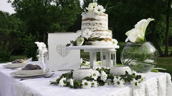 White decoration of the wedding table and a rustic cake in the spring garden.