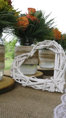 Bahçede cam kavanoz ve wattle beyaz kalp turuncu gül buketleri ile masanın Retro dekorasyon