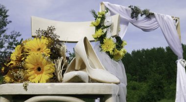 Bir arka planda bir sandalye ve düğün kemer sarı gerbera papatya ve gelinin beyaz ayakkabı Buket - doğada.