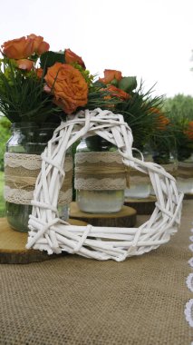 Bahçede cam kavanoz ve wattle beyaz kalp turuncu gül buketleri ile masanın Retro dekorasyon