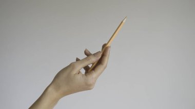  İzole arka planda ahşap renkli bir kalem tutan kadın eli - yakın