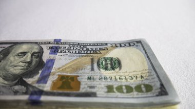 Yüz dolar faturaları beyaz zemin üzerinde bir yığın.