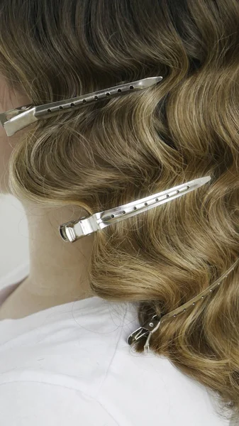 Silver hairdressers clips in wavy hair - close up