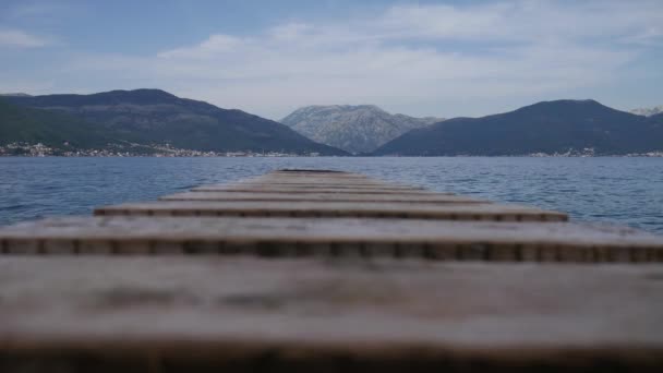 ビキニを着た女性が海と山に向かって木製の桟橋を裸足で歩く コトル湾 モンテネグロ — ストック動画