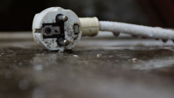 Weißer Stecker Der Bei Regen Auf Dem Boden Liegt — Stockvideo