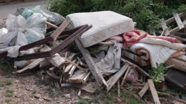 Çöp dökümü: tahtalar, döşek, yorgan, çöp dolu plastik torbalar.