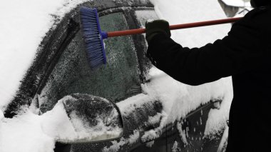 Kar yağdıktan sonra soğuk bir kış günü adam arabayı kardan temizler. Erkeklerin elini fırçala. Arabada çok kar var..