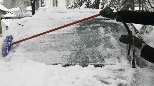 Adamın elleri arabanın ön camındaki karları temizliyor..