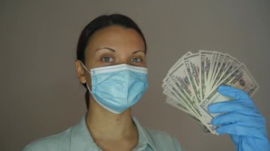 Elli dolarlık banknotların hayranı bir kadın doktor. Tıbbi maskeli ve eldivenli hemşire para kokusu alıyor..