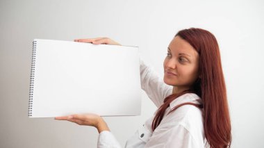 Beyaz kadın elinde boş tuval pedi tutuyor..