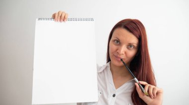 Sanatçı kadın elinde boş tuval pedi tutuyor. Metin veya logo için boşluk negatif veya kopyala.