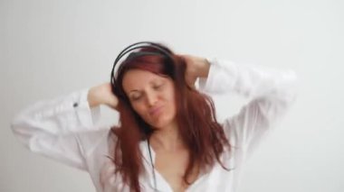 Gülümseyen beyaz kadın siyah kulaklıklardan müzik dinliyor..