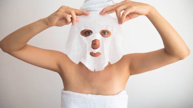 Kadın beyaz kozmetik maskeyi takıyor ya da çıkarıyor..