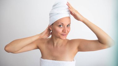 Makyajsız kadın beyaz havluya sarılmış..