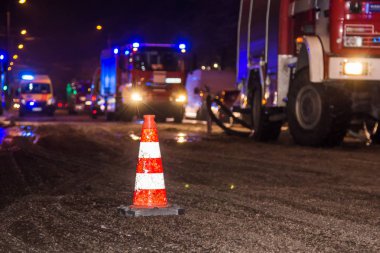 Yangın söndürme itfaiye araçları ve ambulanslar arka plan üzerinde akşam kışın sırasında yolda bir koni