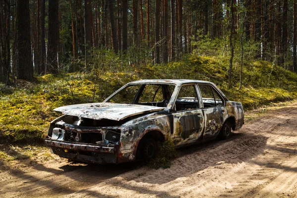 Voll ausgebranntes Auto im Wald in Spirng auf sandiger Straße — Stockfoto