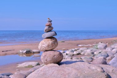 Güneşli bir günde Baltık Denizi 'nin kayalık sahillerinde taşların Zen dengesi